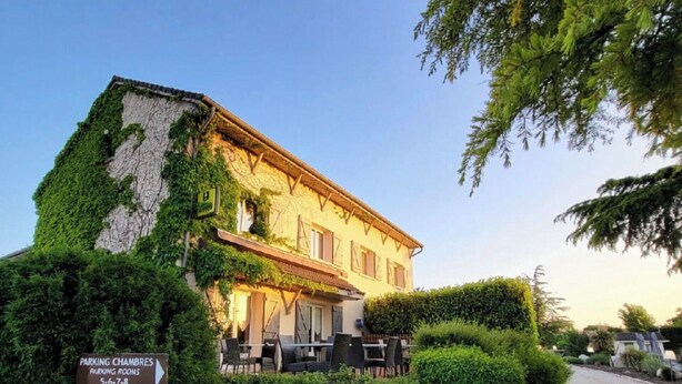 A building with a stone facade and ivy growth, surrounded by well-maintained hedges and a gravel path leading to the entrance. - Hôtel Parc Adélie (Montagny-les-Beaune)