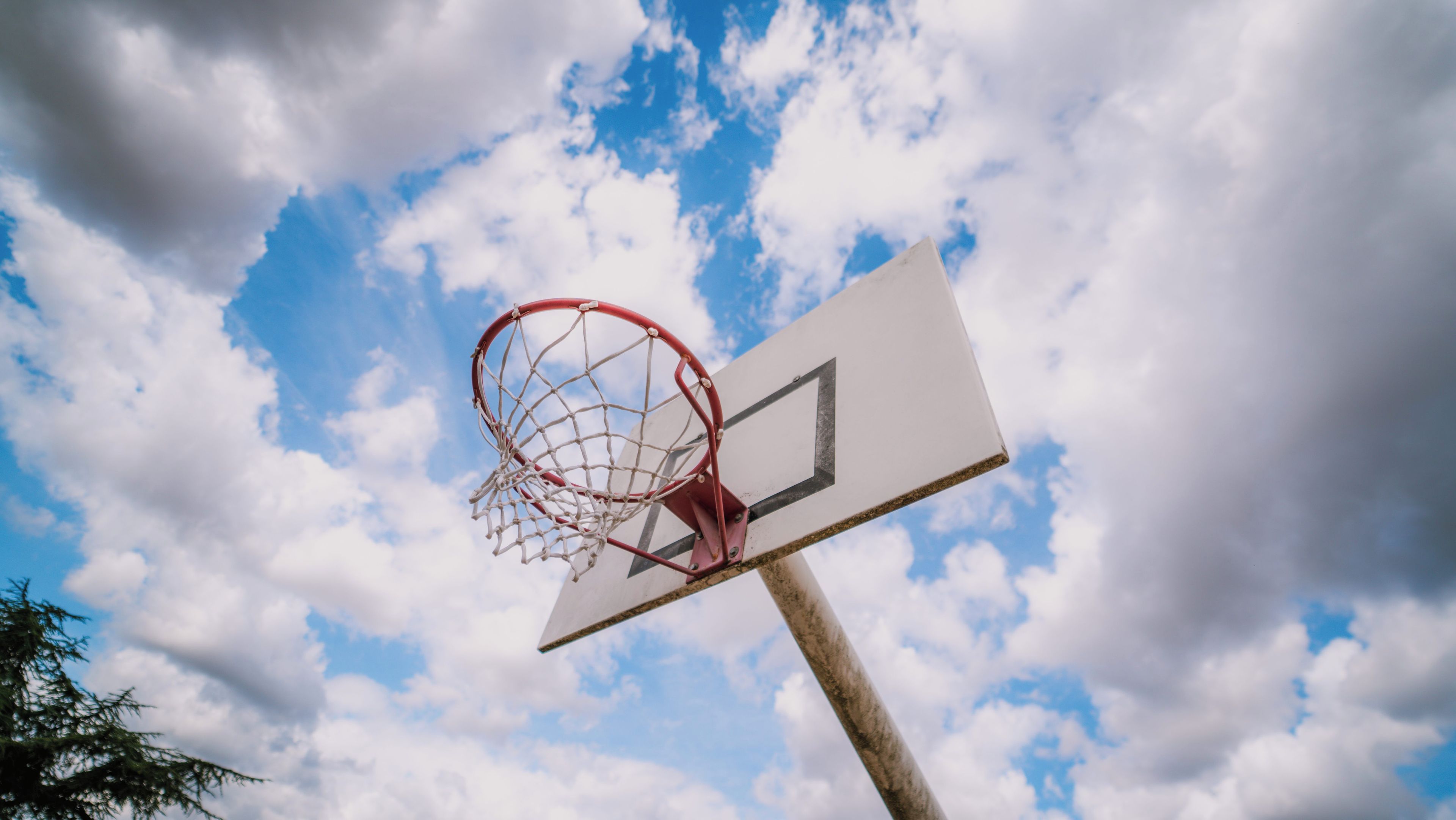 En basketballkurv mod en himmel med skyer.