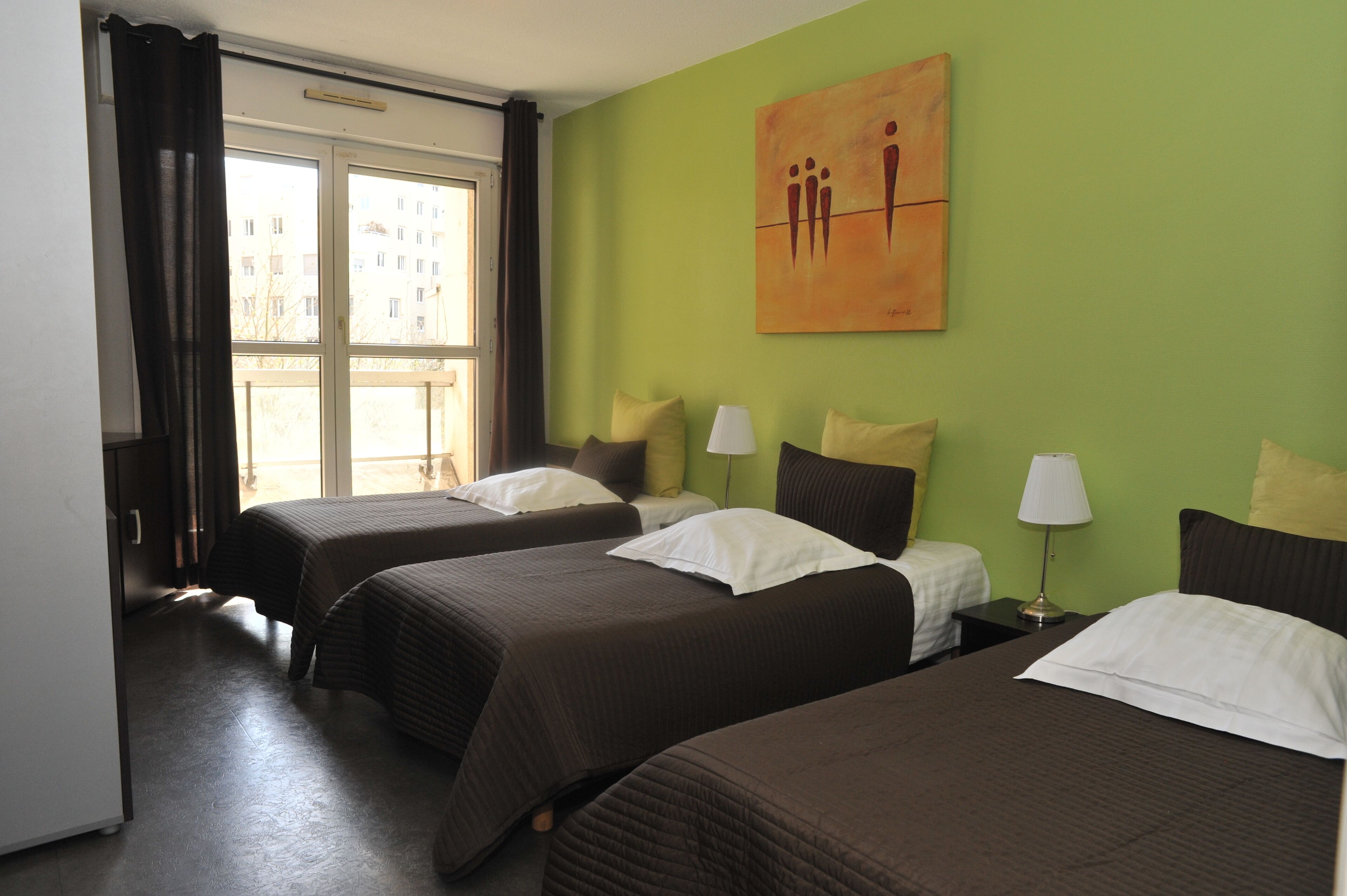 Una habitación de hotel con dos camas, una pared verde, un cuadro y una ventana con cortinas.