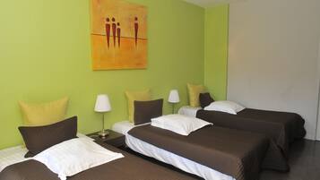 A hotel room with three beds, each with brown bedding and white pillows. There is a painting on the wall above the beds.