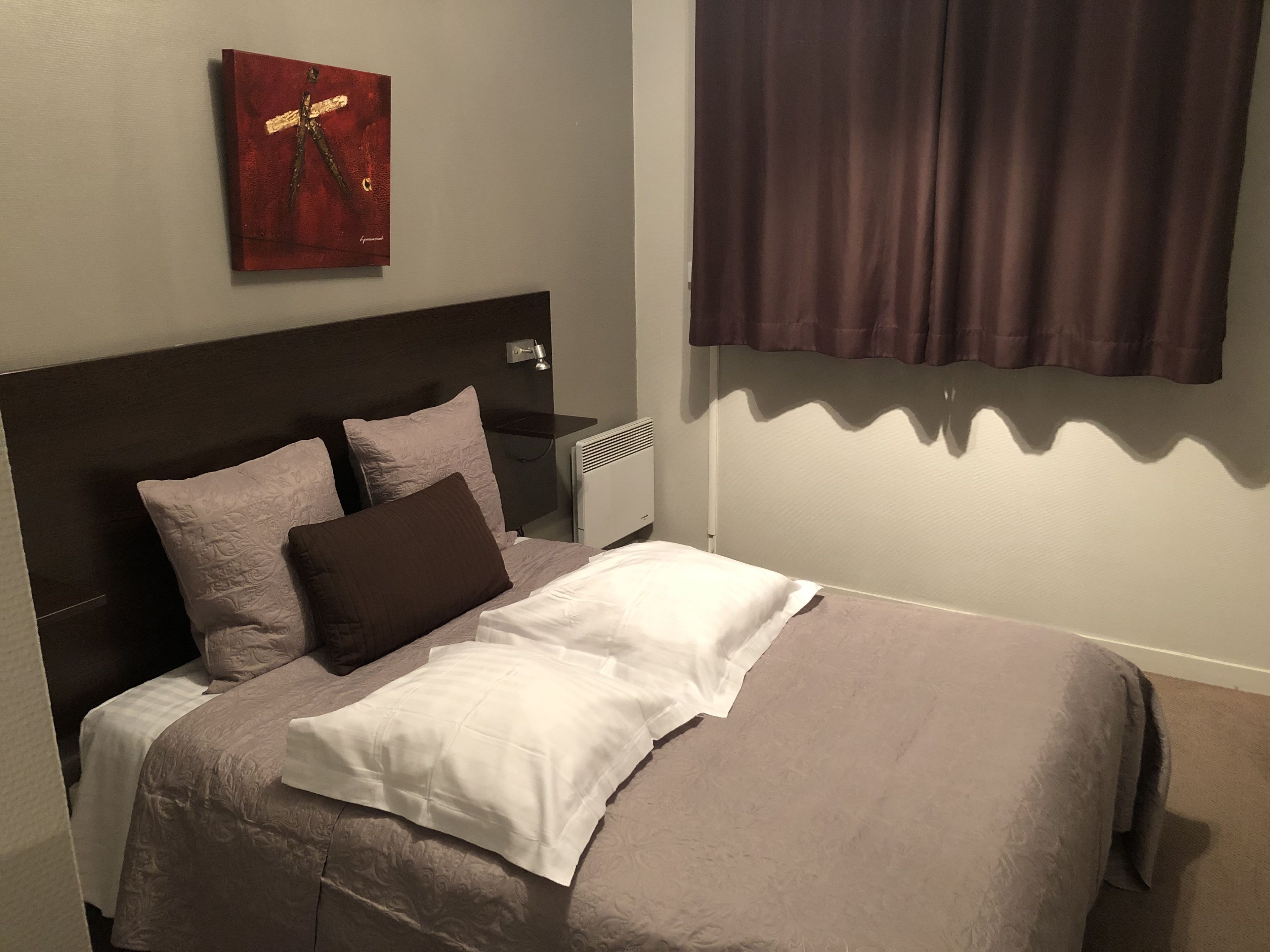 A neatly made bed with a headboard, two pillows, and a white blanket.