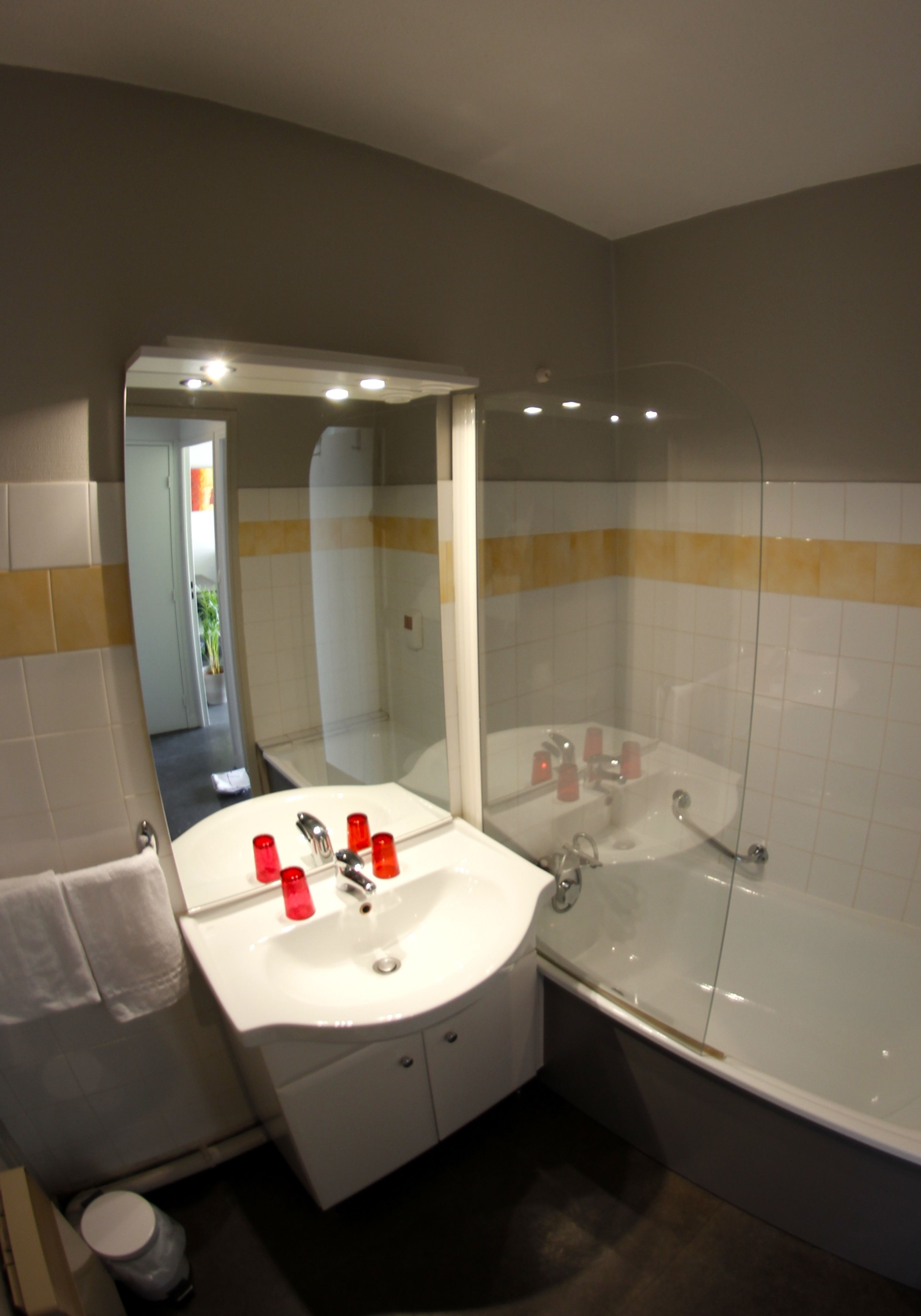 Een badkamer met een wastafel, spiegel en bad.