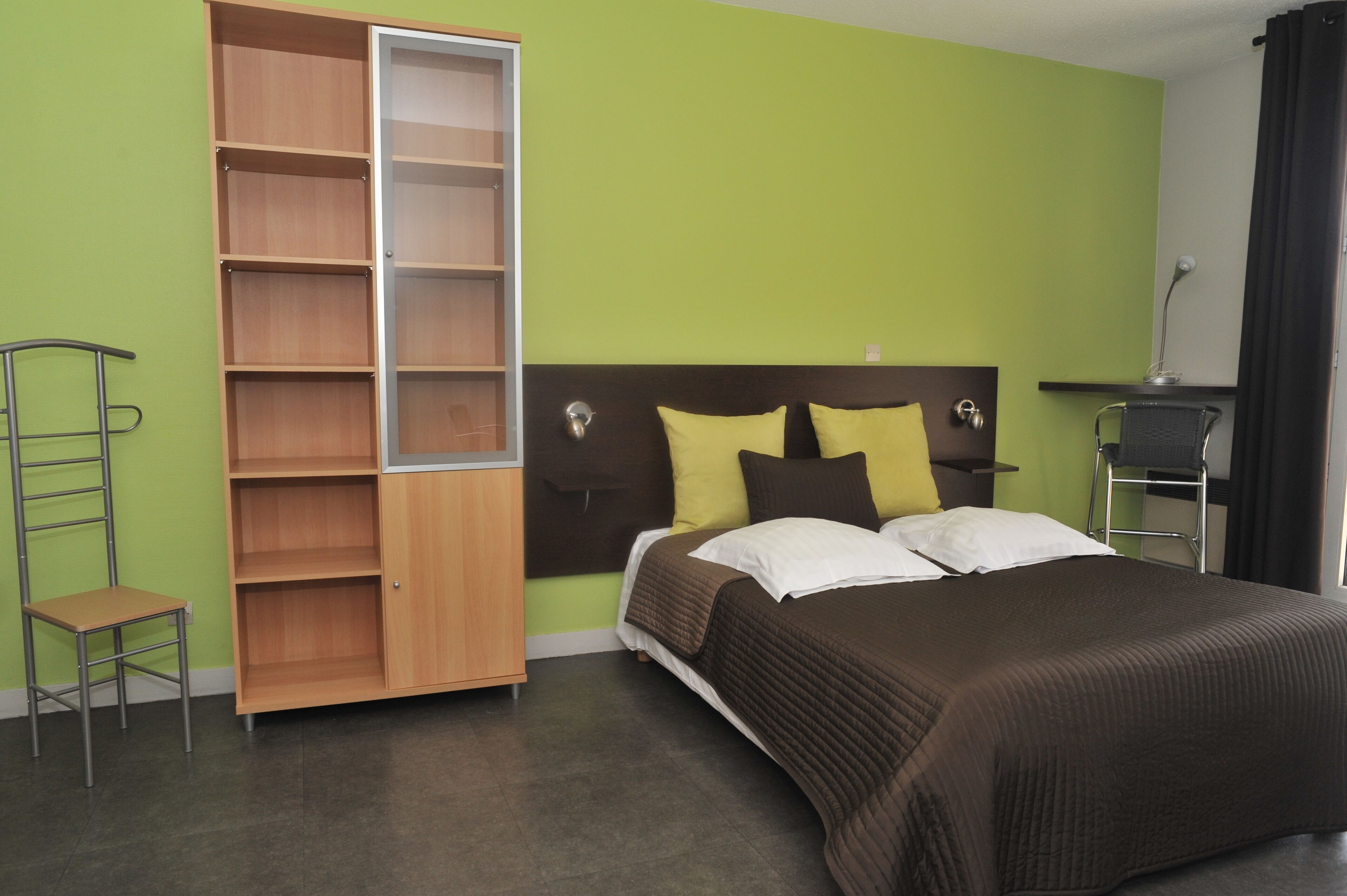 Ein Schlafzimmer mit Bett, Kleiderschrank, Sessel und Schreibtisch.