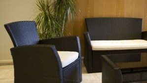 A room with two wicker chairs, a sofa, and a small table with a remote control. - Les Palatines - Residence (Saint-Etienne)
