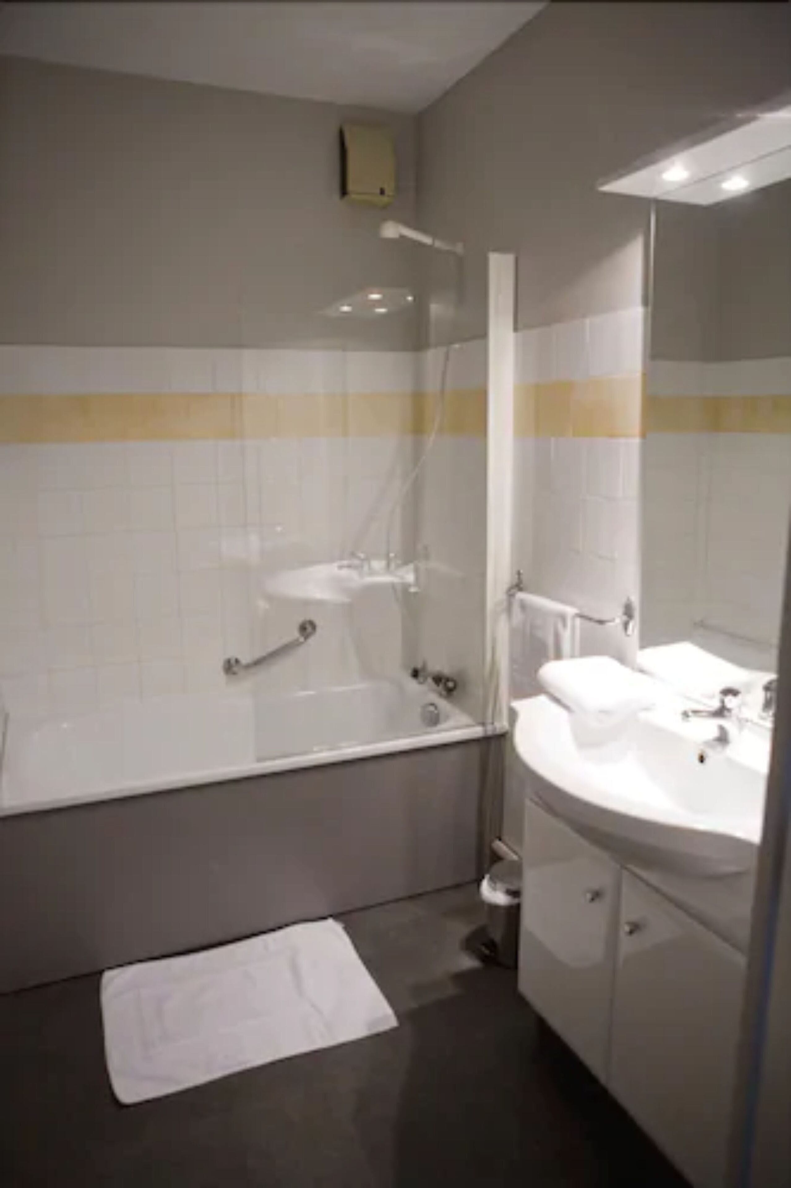 Un bagno con una vasca, un lavandino, uno specchio e un portasciugamani.