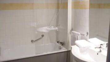 A bathroom with a bathtub, a sink, a mirror, and a towel rack.