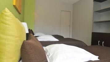 Quarto de hotel com duas camas, uma porta e uma estante.