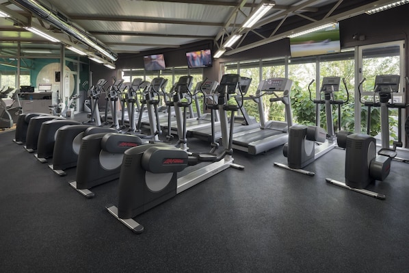 Un gimnasio con cintas de correr, elípticas y máquinas de pesas.
