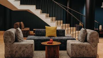 Una sala de estar moderna con una escalera, dos sofás, una mesa de centro y un cojín amarillo.