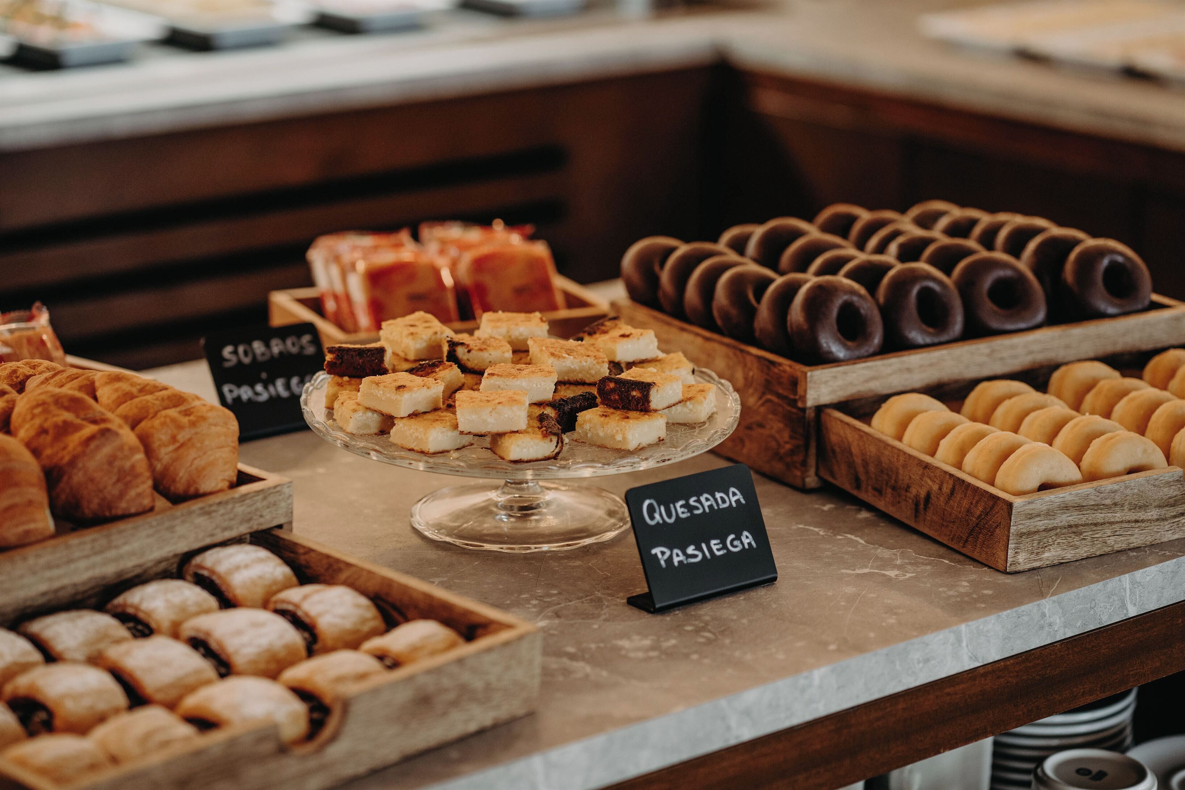 A bakery display with various pastries and baked goods, including a sign for queso pasiego.