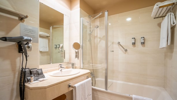 Un baño moderno con ducha separada por vidrio, lavamanos y espejo.