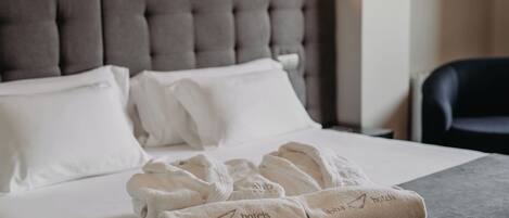 Una cama bien hecha con sábanas blancas y un juego de toallas con el logotipo de 'abha hotels'.