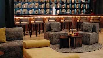 A modern lounge area with sofas, armchairs, and a bar with shelves of bottles.