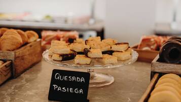A display of pastries and bread, including a sign labeled "Quesada Pasiega".