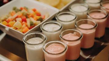 A tray with various food items including a fruit salad and several small glasses of different colored beverages.