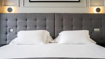 A neatly made bed with white linens and a grey tufted headboard.