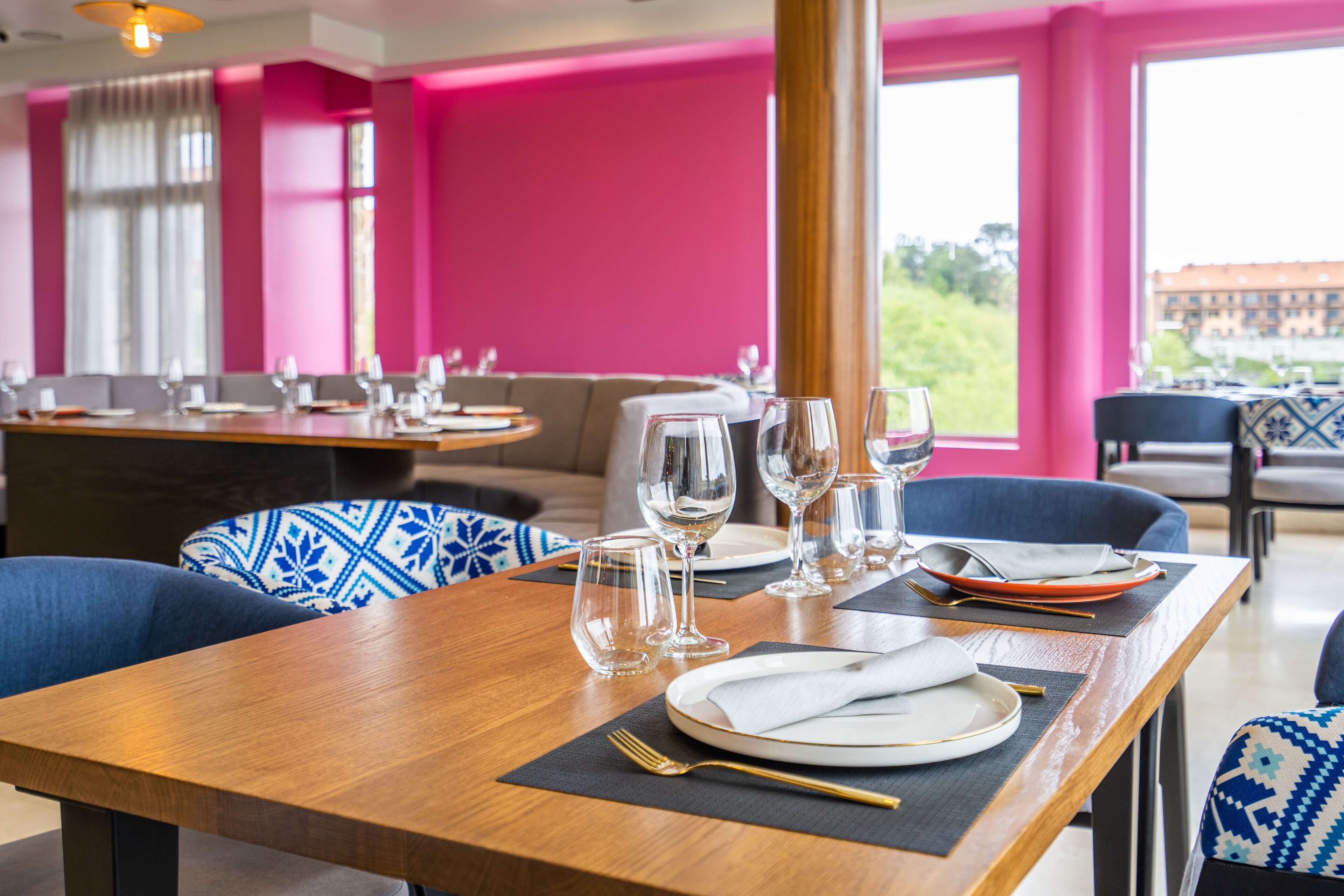 Un restaurante con mesas dispuestas para comer, que presenta un interior luminoso y grandes ventanales.