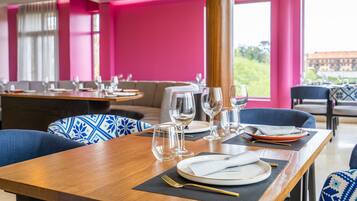Un restaurante con mesas dispuestas para comer, que presenta un interior luminoso y grandes ventanales.