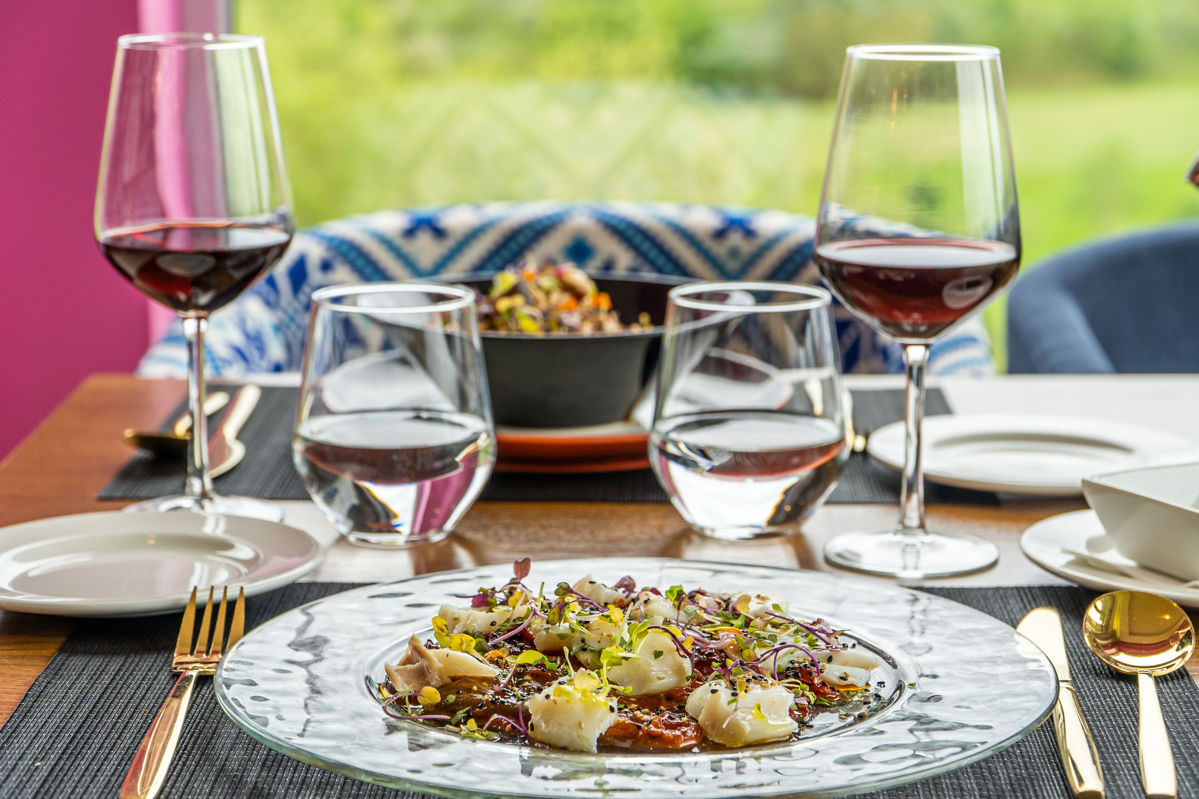 A dining table with a plate of food, wine glasses, and cutlery.