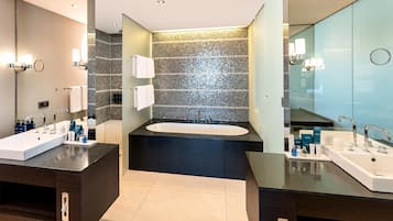 Un baño moderno con dos lavamanos, una bañera grande y una cabina de ducha de vidrio.