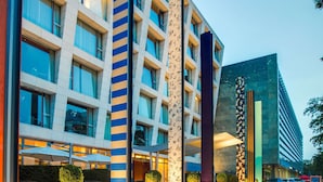 A modern hotel with a geometric facade, outdoor seating area, and potted plants. - Radisson Blu Media Harbour Hotel, Düsseldorf (Düsseldorf)