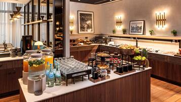 A buffet setup with various food items, a juice station, and decorative wall lights.