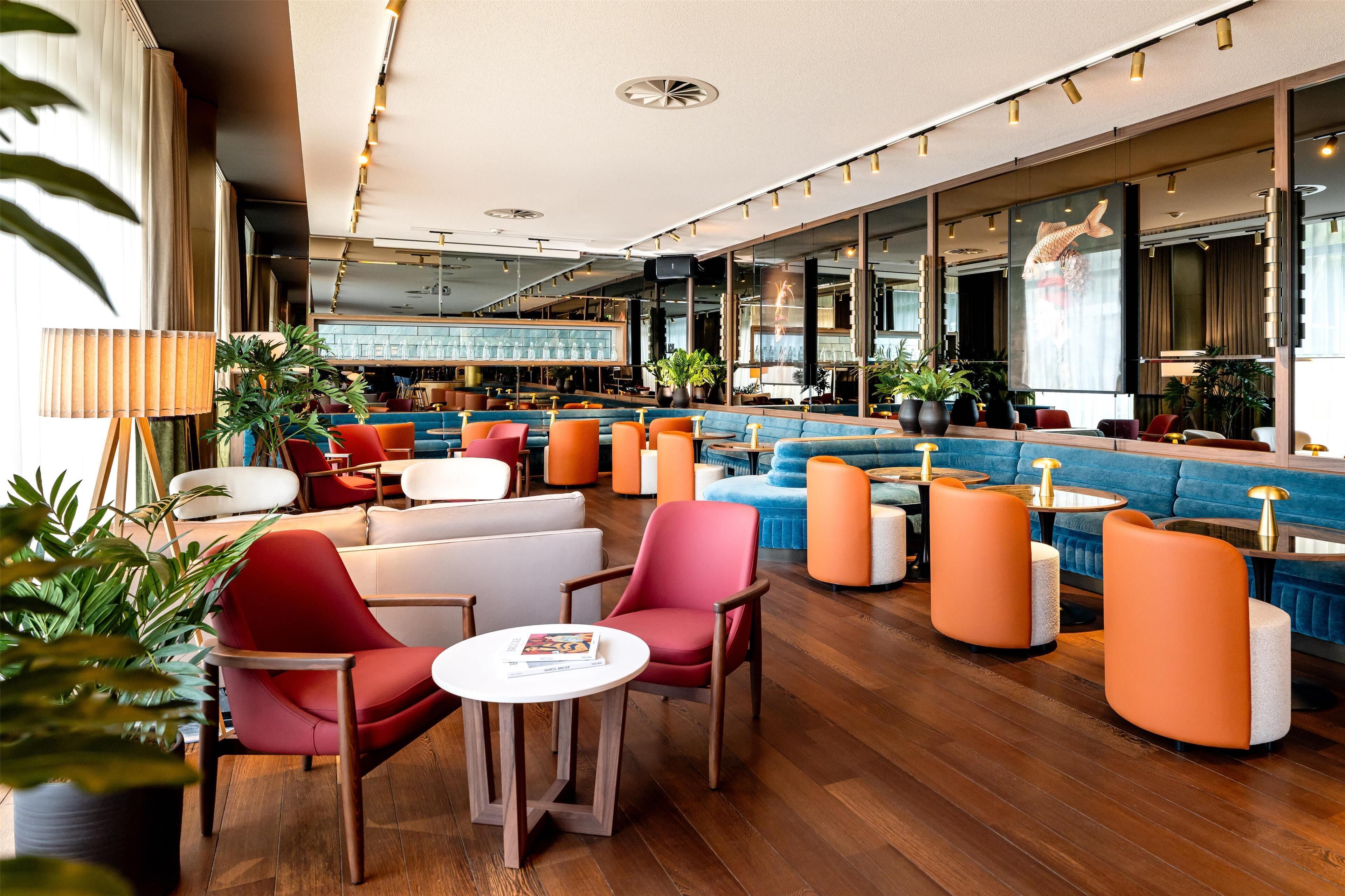 Un área de estar moderna con disposición de asientos, un bar y ventanas amplias.