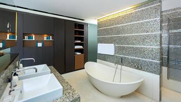 A modern bathroom with a freestanding bathtub, a double sink vanity, and built-in shelving.
