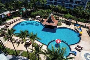 Une grande piscine avec un toboggan, entourée de chaises longues et de palmiers.