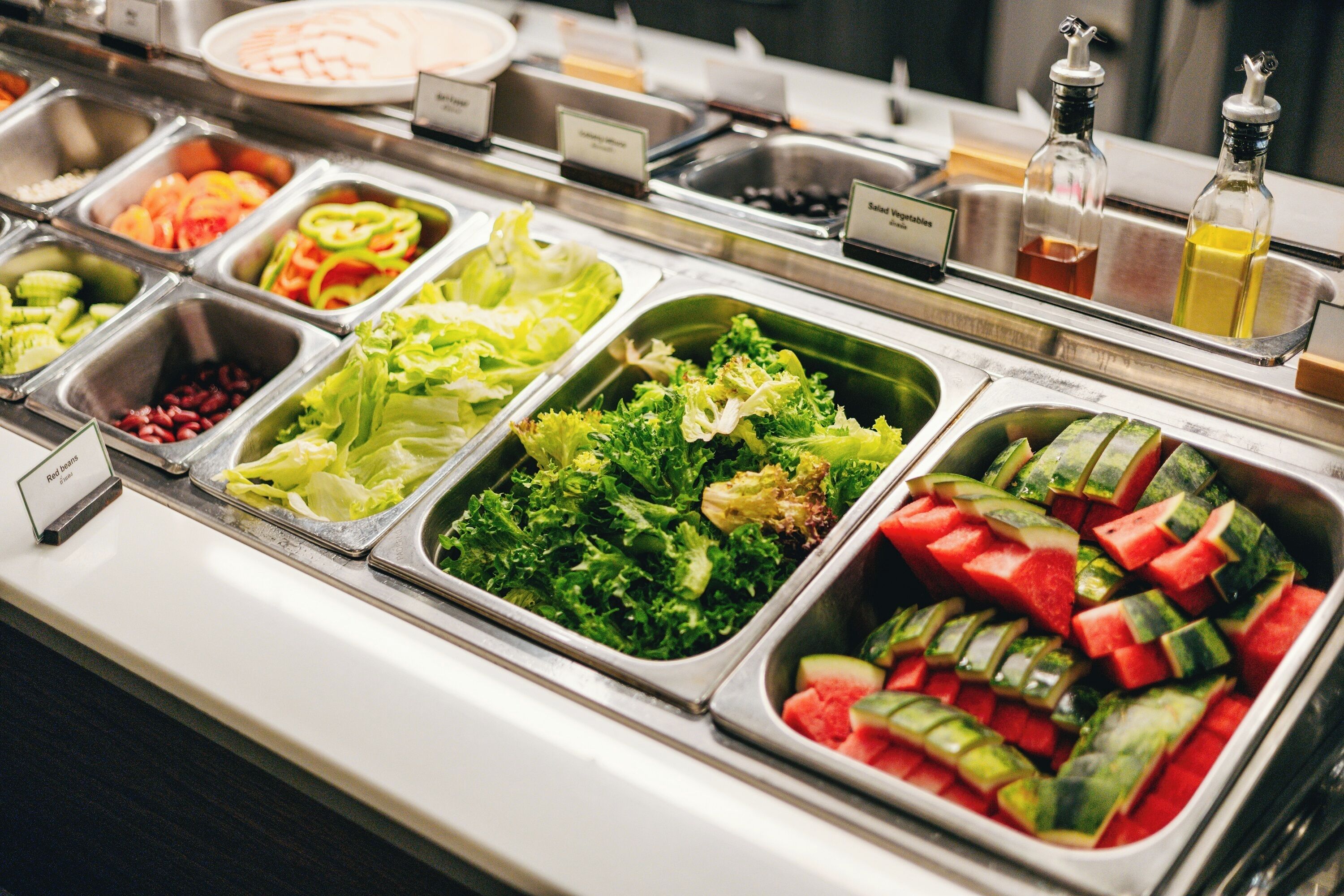 Un buffet proposant une variété de plats, notamment des salades, des légumes et des fruits.