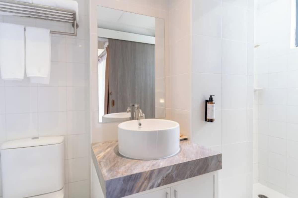 Une salle de bain moderne avec un lavabo rond blanc, un miroir et un porte-serviettes.