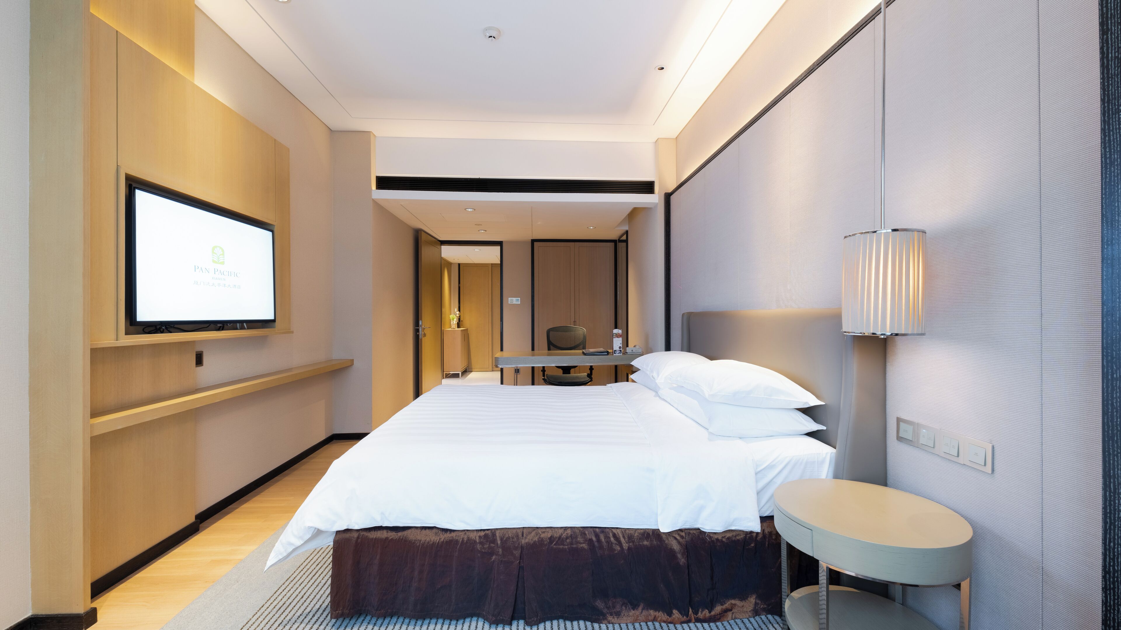 Ein modernes Hotelzimmer mit einem großen Bett, einem Schreibtisch, einem Fernseher und einer Lampe.