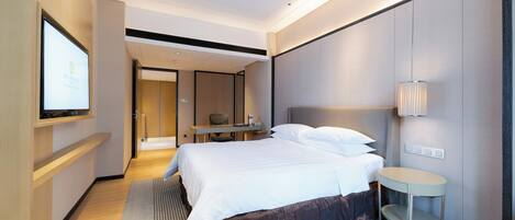 Una habitación de hotel moderna con una cama grande, una mesita de noche y un televisor montado en la pared.