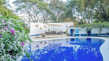 Una piscina al aire libre, sillones reclinables de piscina