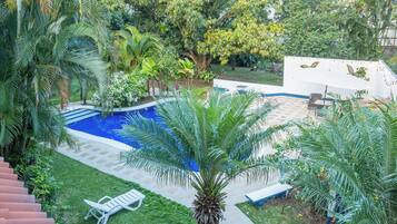 A backyard with a swimming pool, palm trees, and outdoor furniture.