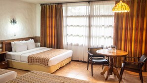 A hotel room with a bed, a dining table with chairs, and curtains. - Hotel Aeropuerto (San Antonio)