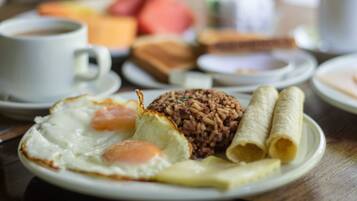 A breakfast plate with fried egg, rice, and rolled omelette.