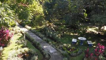 Un jardín con un sendero sinuoso, una pequeña mesa y bancos.