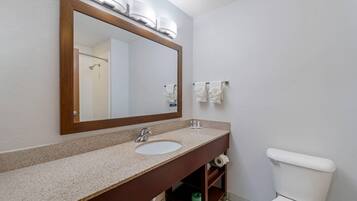 A bathroom with a wooden-framed mirror, a sink, and a toilet.