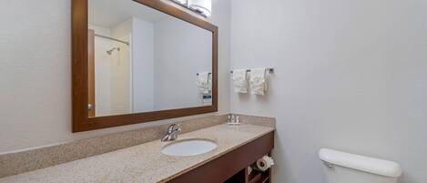 Un baño con un espejo de marco de madera, un lavamanos y un inodoro.