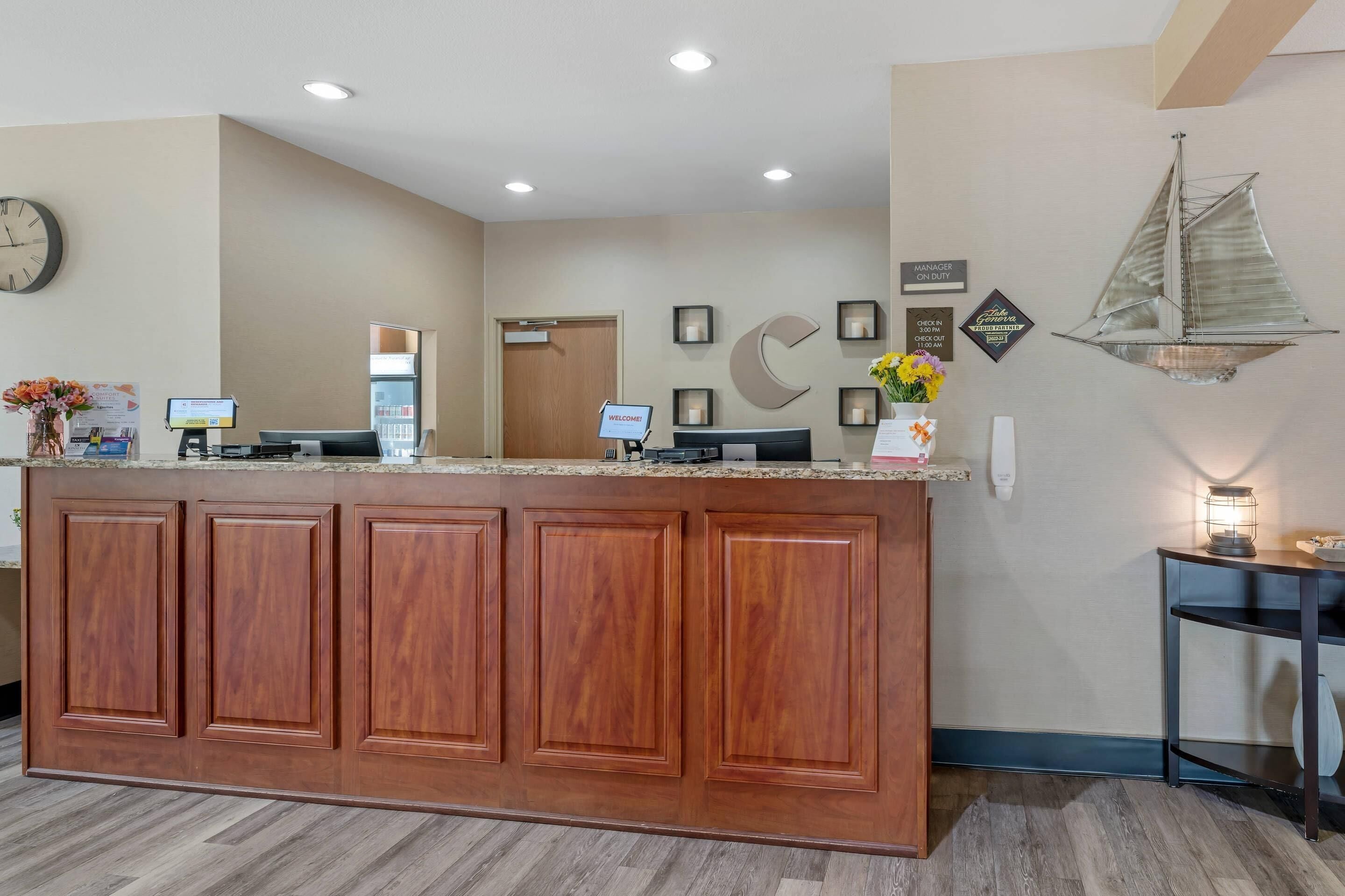 A reception area with a wooden counter, a clock, and a wall-mounted sailboat decoration.