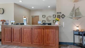 A reception area with a wooden counter, a clock, and a wall-mounted sailboat decoration.