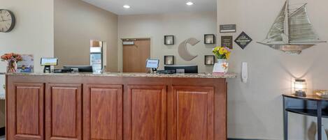 A reception area with a wooden counter, a clock, and a wall-mounted sailboat decoration.
