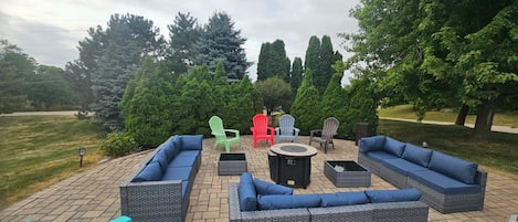 An outdoor patio area with wicker furniture, including sofas and chairs, and a round table.