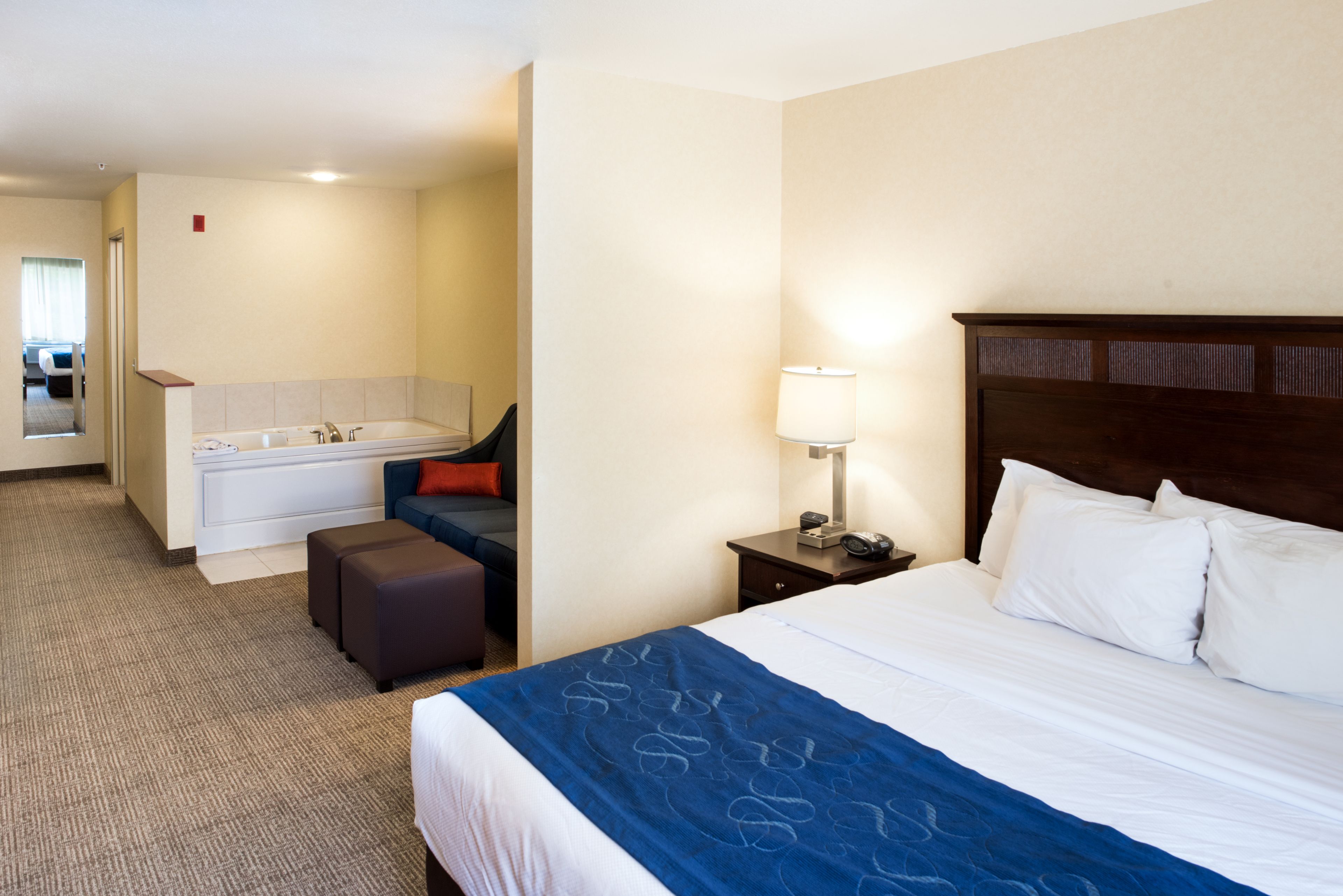 Ein Hotelzimmer mit einem großen Bett, einem separaten Badezimmer mit einer Badewanne, einem Schreibtisch und einem Stuhl.