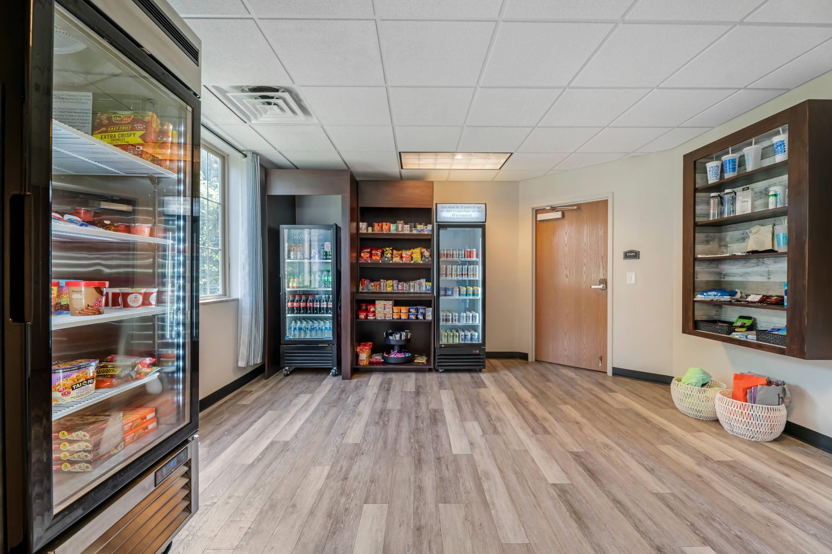 A clean, well-lit hallway with refrigerated display cases and shelves stocked with snacks and beverages.