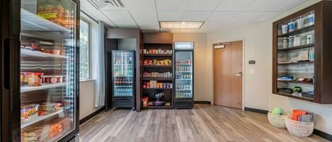 A clean, well-lit hallway with refrigerated display cases and shelves stocked with snacks and beverages.