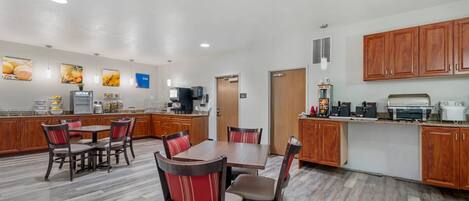 A modern kitchen with wooden cabinets, a dining area with chairs, and a countertop with appliances.