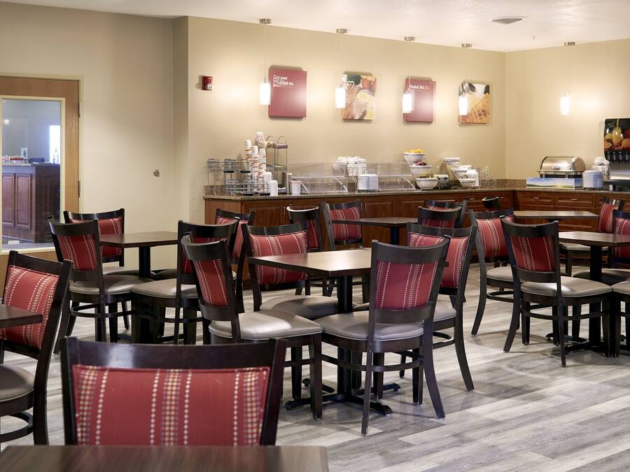 Een restaurantgedeelte in een hotel met meerdere tafels en stoelen, een buffet en een keuken op de achtergrond.