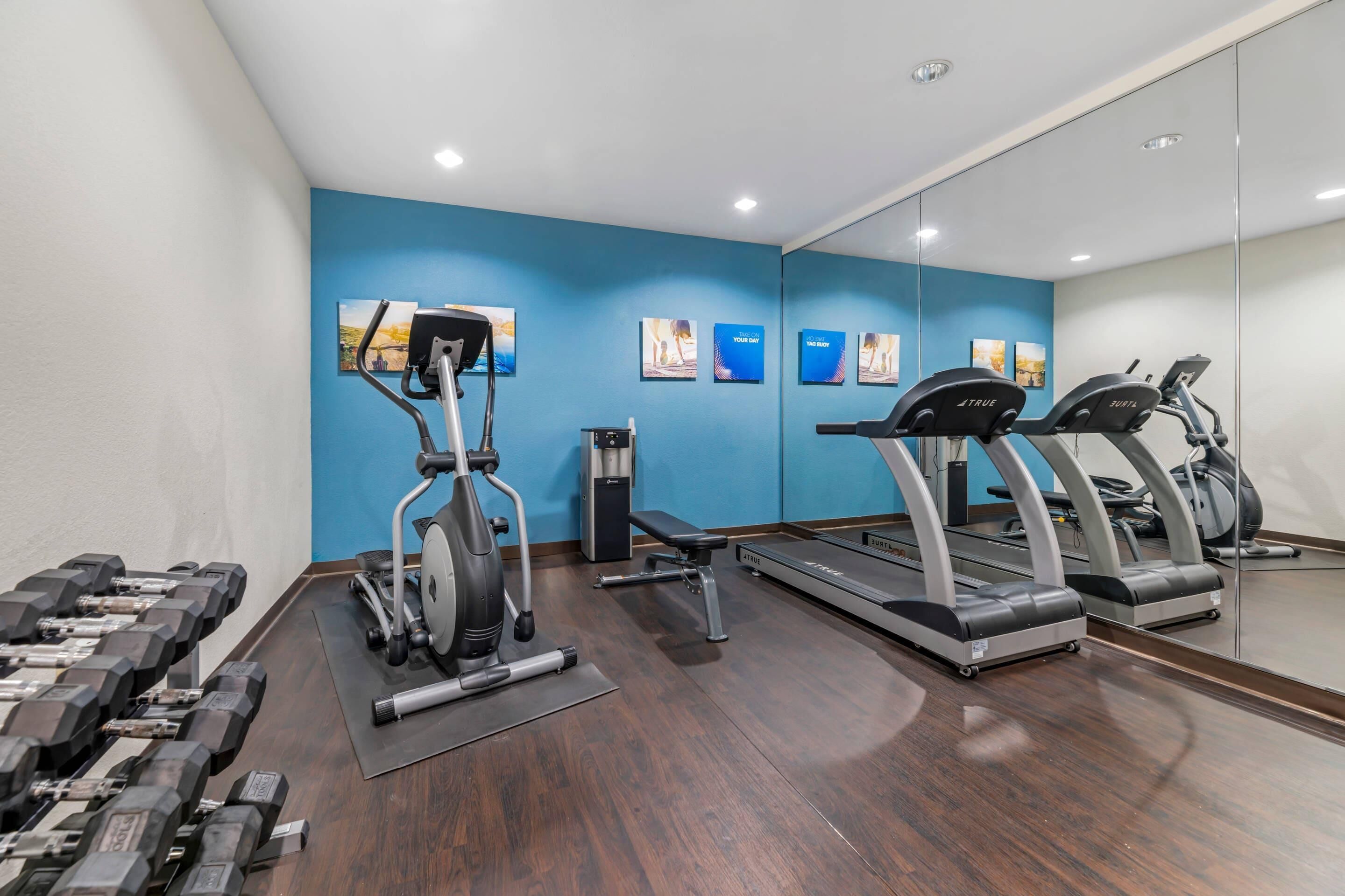 A gym with exercise equipment, including dumbbells, a stationary bike, and treadmills.